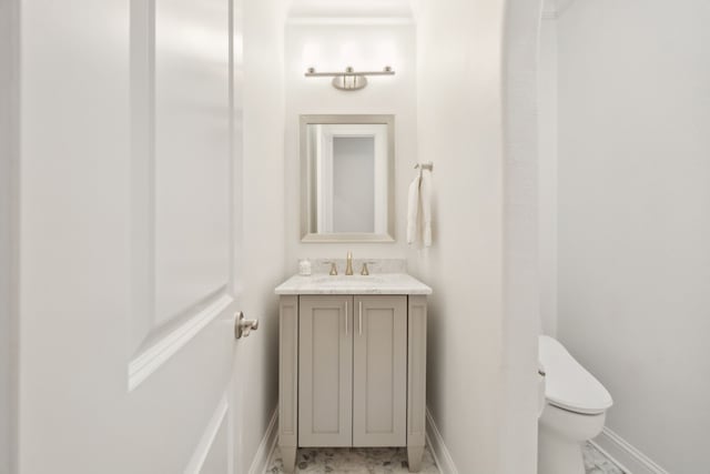 half bathroom with toilet, baseboards, and vanity