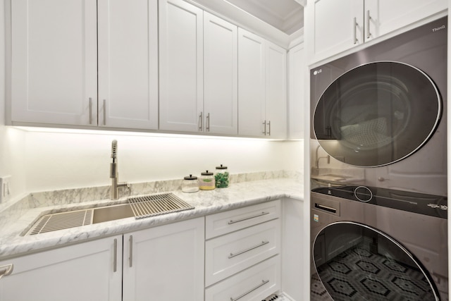 washroom featuring stacked washer and dryer, cabinet space, and a sink