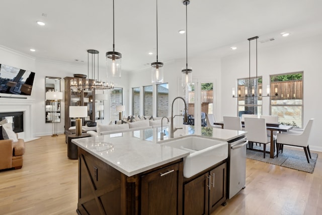 kitchen with dark brown cabinetry, light wood-style floors, open floor plan, and a sink