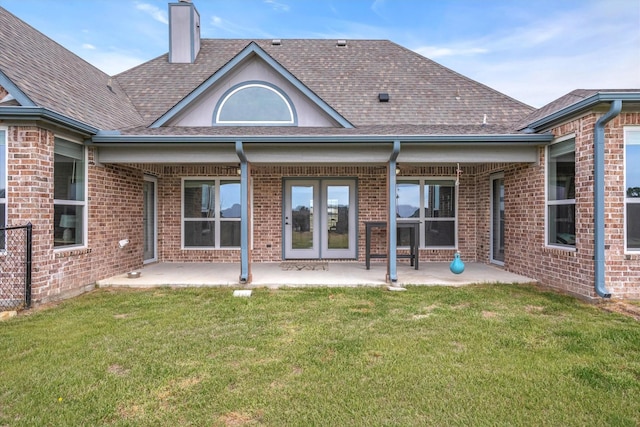 back of property featuring a patio area, a lawn, a chimney, and roof with shingles