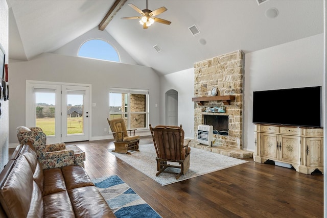 living room featuring dark wood-style floors, beam ceiling, visible vents, a stone fireplace, and high vaulted ceiling