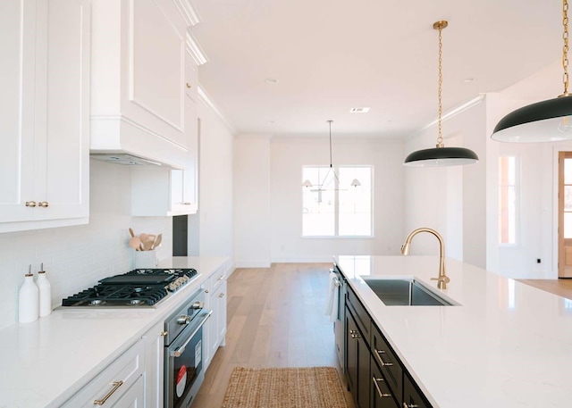 kitchen with white cabinets, ornamental molding, stainless steel appliances, and a sink