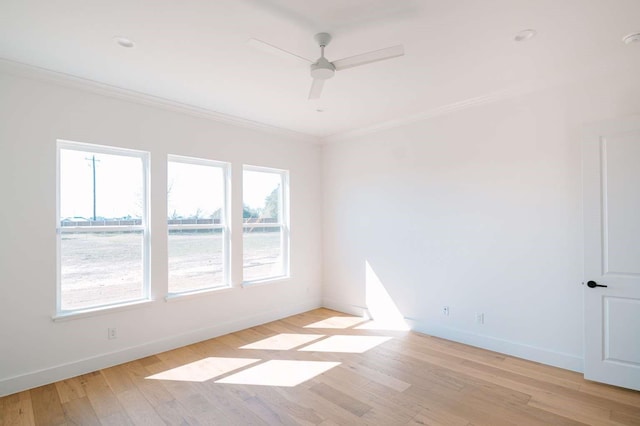 empty room with baseboards, ceiling fan, light wood finished floors, and crown molding