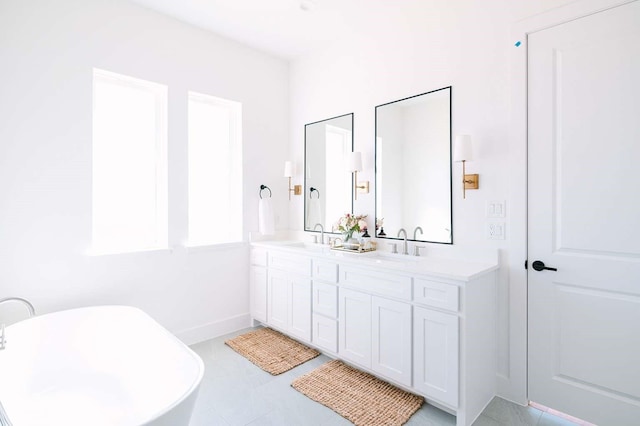 full bathroom featuring a freestanding tub, a sink, baseboards, and double vanity