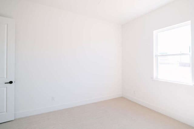 unfurnished room featuring light carpet and baseboards