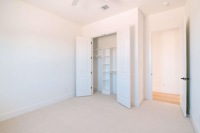 unfurnished bedroom featuring light carpet, baseboards, visible vents, a ceiling fan, and a closet