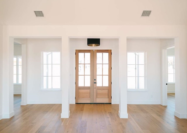 entryway with light wood finished floors, plenty of natural light, visible vents, and french doors