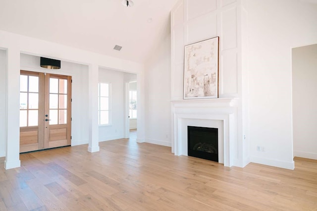 unfurnished living room with light wood-style flooring, a fireplace, visible vents, and baseboards