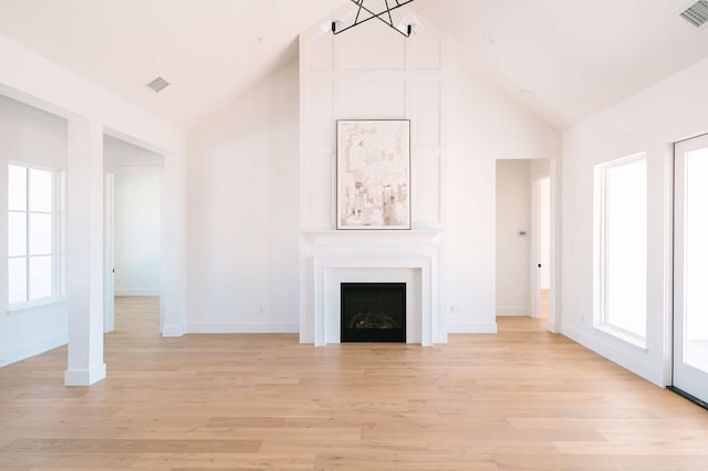 unfurnished living room featuring light wood-type flooring, a fireplace, high vaulted ceiling, and visible vents