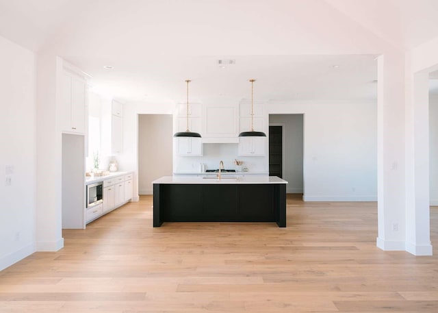 kitchen with light wood-style floors, light countertops, white cabinets, and a sink