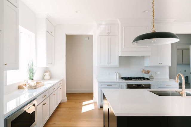 kitchen with gas cooktop, light countertops, stainless steel microwave, and a sink