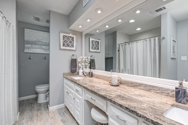 full bathroom featuring visible vents, toilet, vanity, wood finished floors, and baseboards