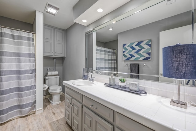 full bathroom featuring toilet, vanity, wood finished floors, and visible vents