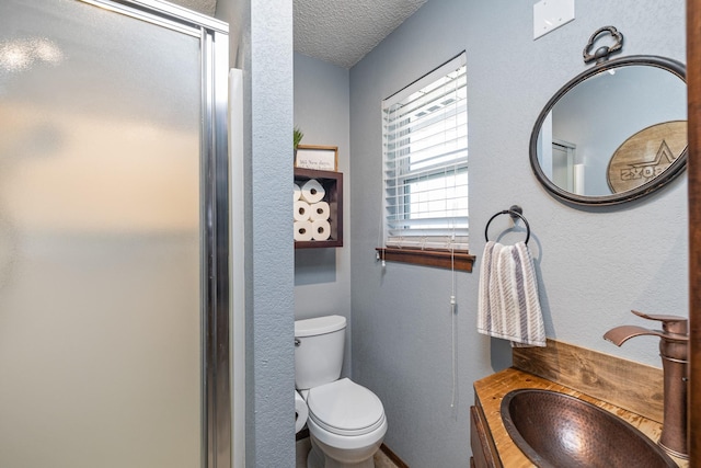 full bath with a textured wall, toilet, a stall shower, a textured ceiling, and vanity