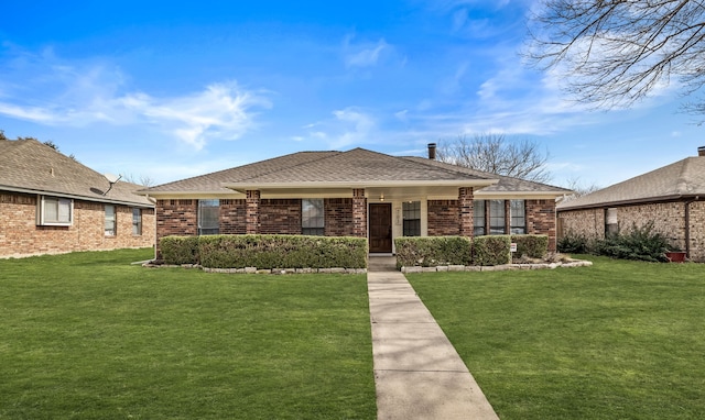 view of front of home with a shingled roof, a front lawn, and brick siding