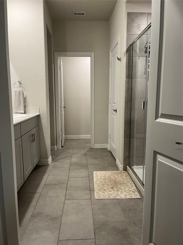 full bathroom with a stall shower, vanity, visible vents, and baseboards