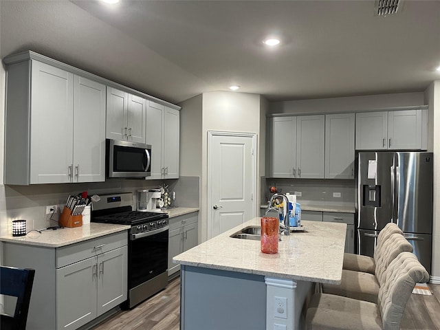 kitchen featuring a breakfast bar area, wood finished floors, a sink, visible vents, and appliances with stainless steel finishes