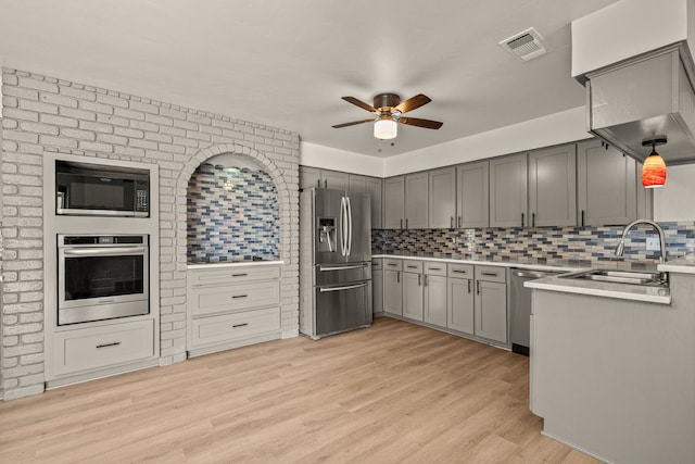 kitchen featuring appliances with stainless steel finishes, gray cabinets, visible vents, and light wood-style floors