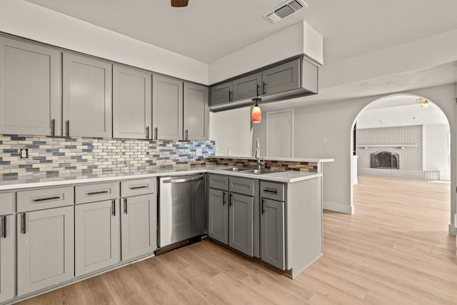 kitchen featuring a peninsula, a sink, visible vents, gray cabinets, and dishwasher