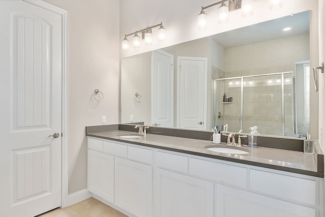 bathroom featuring a stall shower, tile patterned flooring, a sink, and double vanity