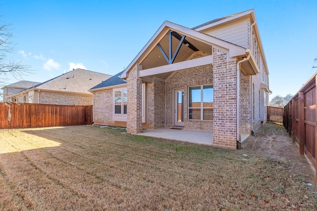 back of house with a yard, brick siding, a patio, and a fenced backyard