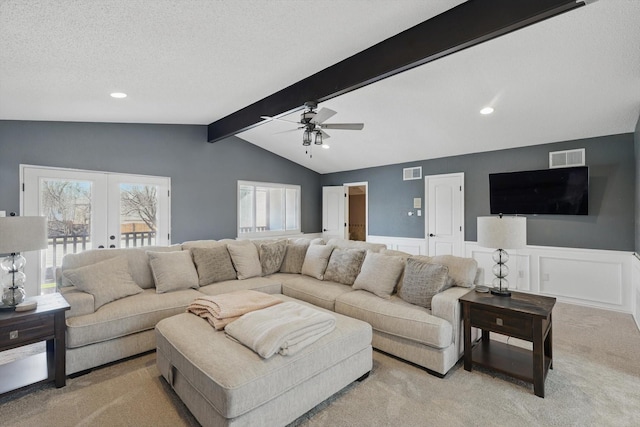 carpeted living room featuring lofted ceiling with beams, french doors, visible vents, and wainscoting