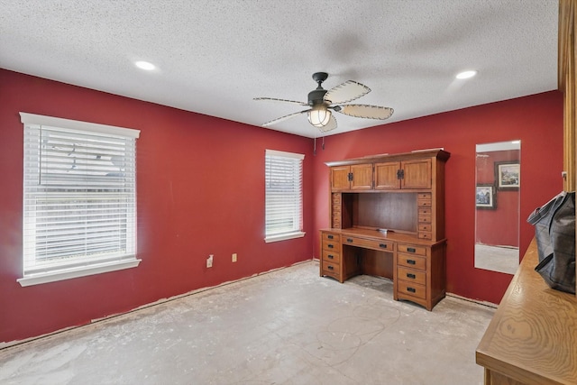 office area with a healthy amount of sunlight, a textured ceiling, concrete flooring, and a ceiling fan