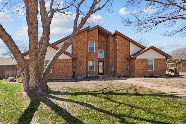 rear view of property with brick siding, a lawn, and fence