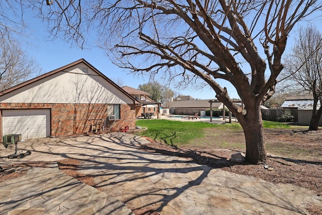 view of side of property featuring brick siding, a fenced in pool, fence, a lawn, and an attached garage