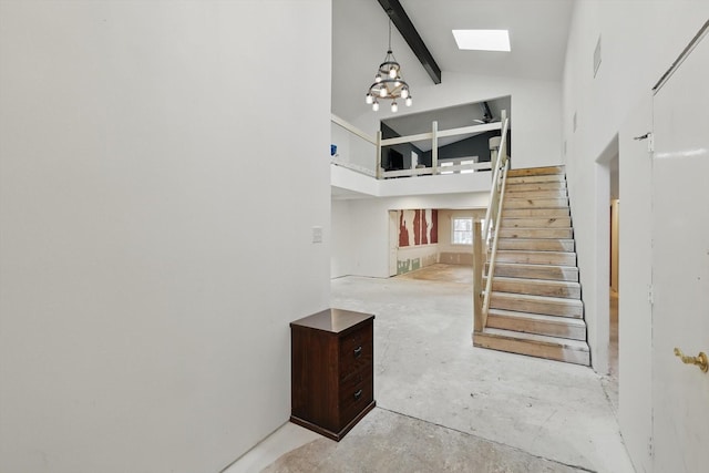 staircase featuring concrete floors, high vaulted ceiling, a skylight, beamed ceiling, and a notable chandelier