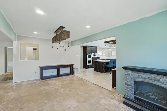 living area with recessed lighting, unfinished concrete flooring, and a stone fireplace