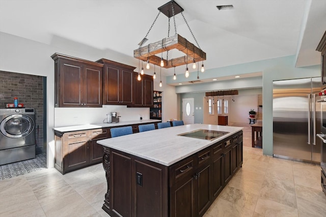 kitchen with visible vents, stainless steel built in refrigerator, vaulted ceiling, washer / dryer, and black electric cooktop