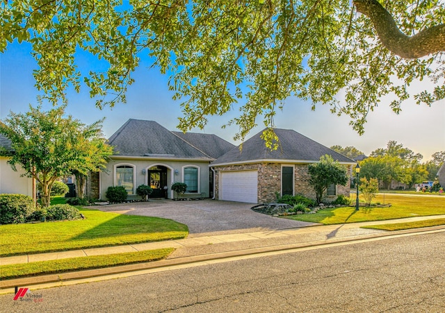 single story home with a garage, a front yard, driveway, and a shingled roof