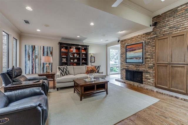 living room with light wood finished floors, a fireplace, visible vents, and crown molding