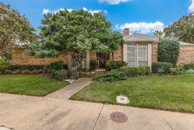 view of front of property with brick siding, a front lawn, and a chimney