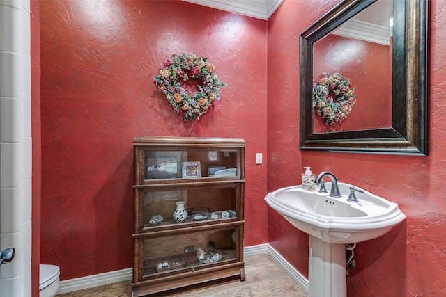 half bathroom featuring baseboards, a textured wall, toilet, and wood finished floors