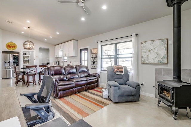 living area with lofted ceiling, ceiling fan, recessed lighting, visible vents, and a wood stove