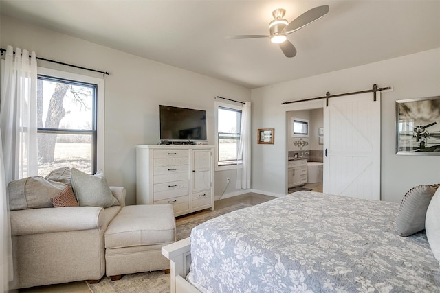 bedroom featuring a barn door, baseboards, a ceiling fan, and ensuite bathroom