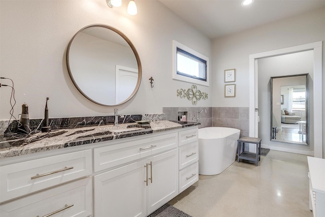 full bath with a soaking tub, tile walls, and vanity