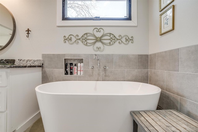 bathroom featuring tile walls, a soaking tub, and vanity