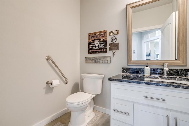 bathroom with baseboards, vanity, and toilet