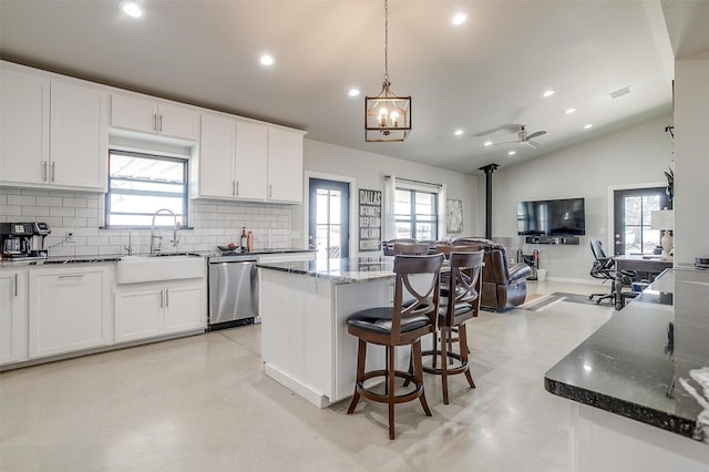 kitchen with finished concrete floors, a wood stove, open floor plan, a sink, and dishwasher