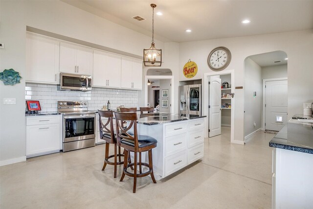 kitchen featuring arched walkways, stainless steel appliances, visible vents, finished concrete flooring, and backsplash