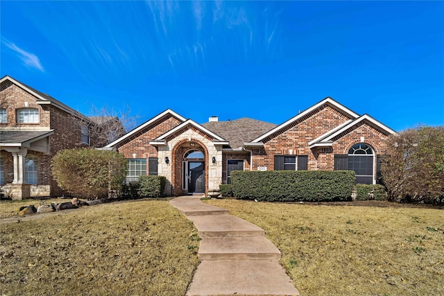 single story home featuring brick siding, a chimney, and a front yard