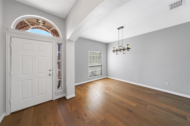 foyer entrance with hardwood / wood-style flooring, baseboards, visible vents, and a chandelier