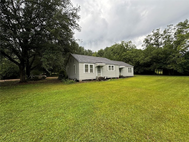 exterior space with a shingled roof and a front yard