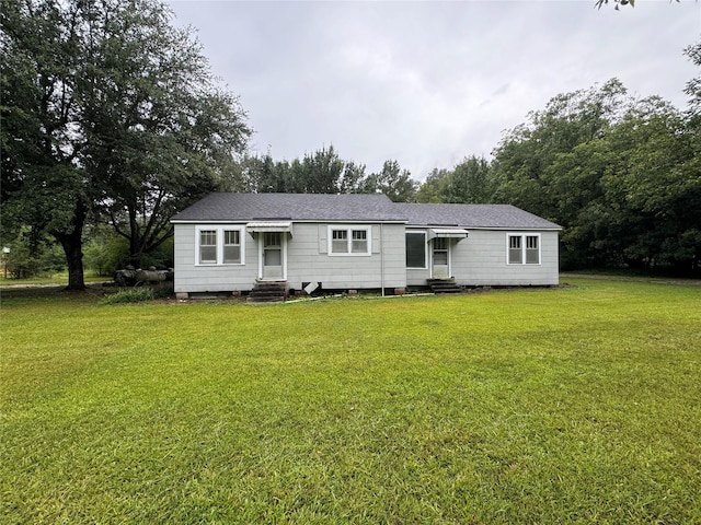 view of front facade featuring entry steps, a front lawn, and roof with shingles