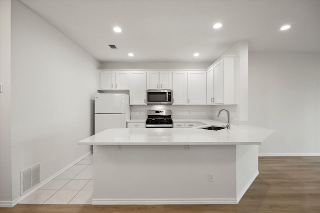 kitchen featuring appliances with stainless steel finishes, visible vents, a sink, and a peninsula