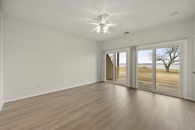 unfurnished room with visible vents, ceiling fan, baseboards, and wood finished floors