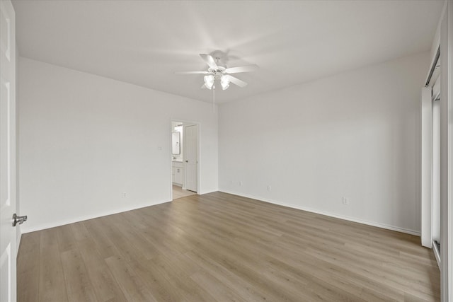 unfurnished bedroom with light wood-type flooring, baseboards, a ceiling fan, and connected bathroom